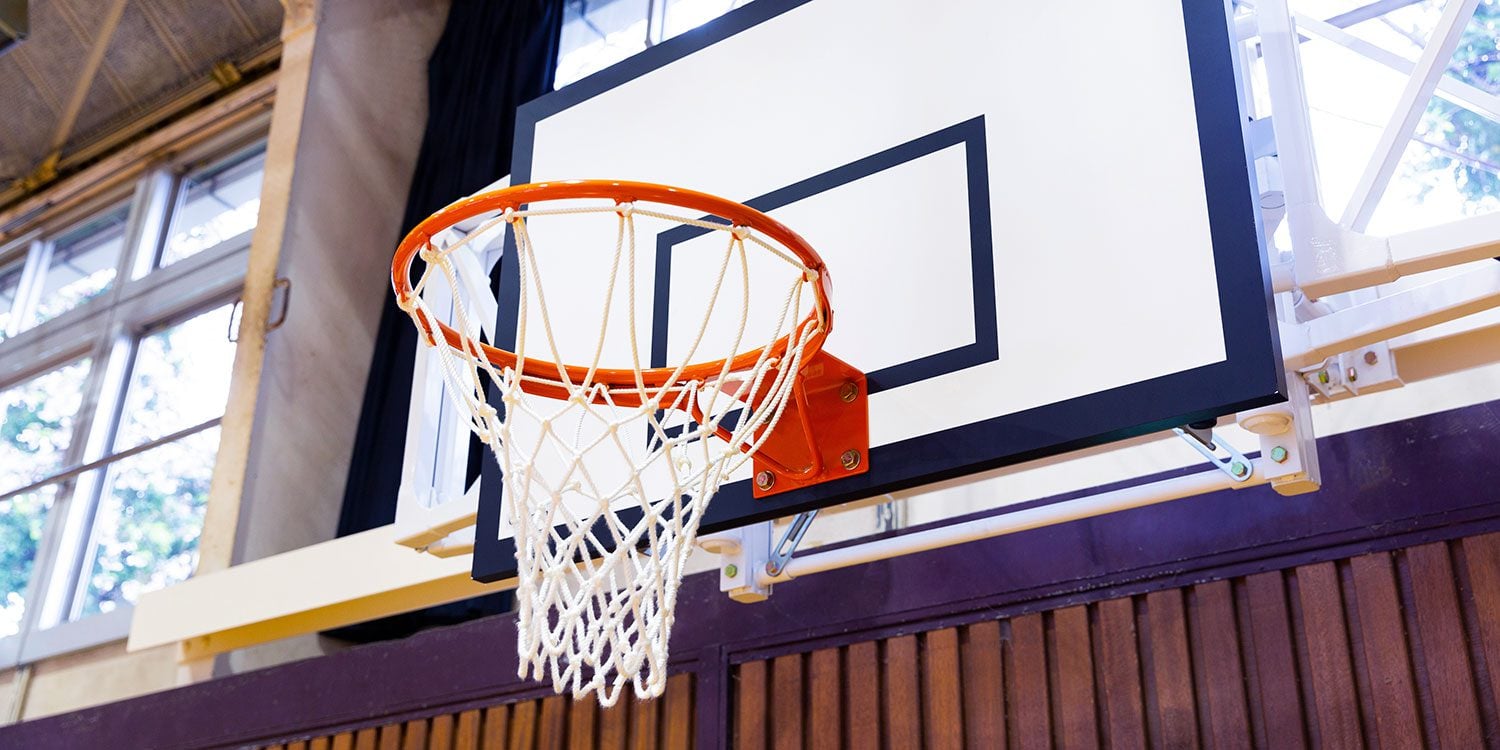Basketball hoop with orange rim and white net, attached to a white backboard.
