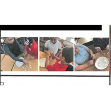 Children at tables with small white objects.