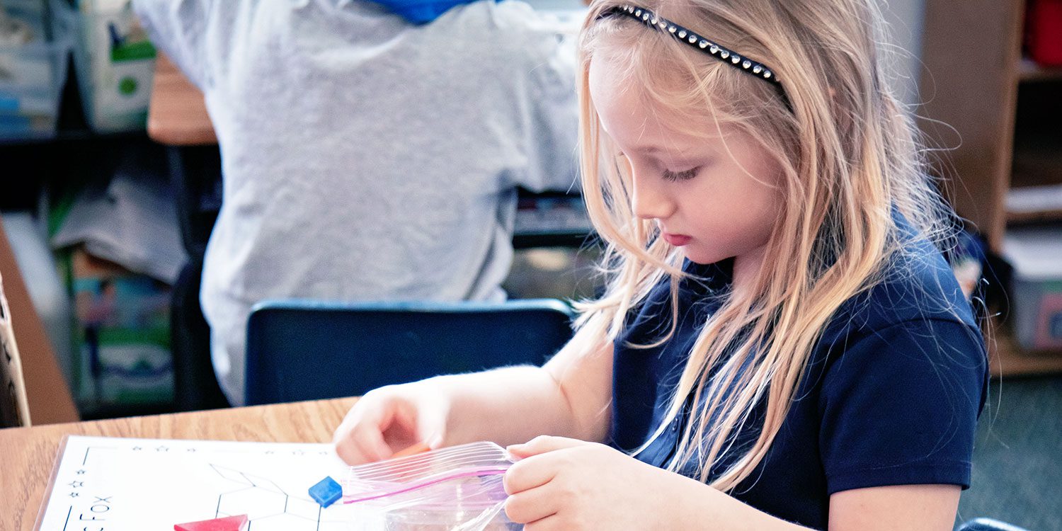 Elementary student working on a shapes activity at their desk.