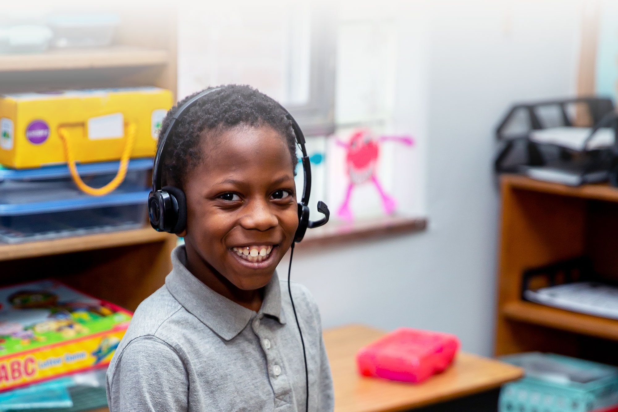 A smiling student wearing a headset in a classroom