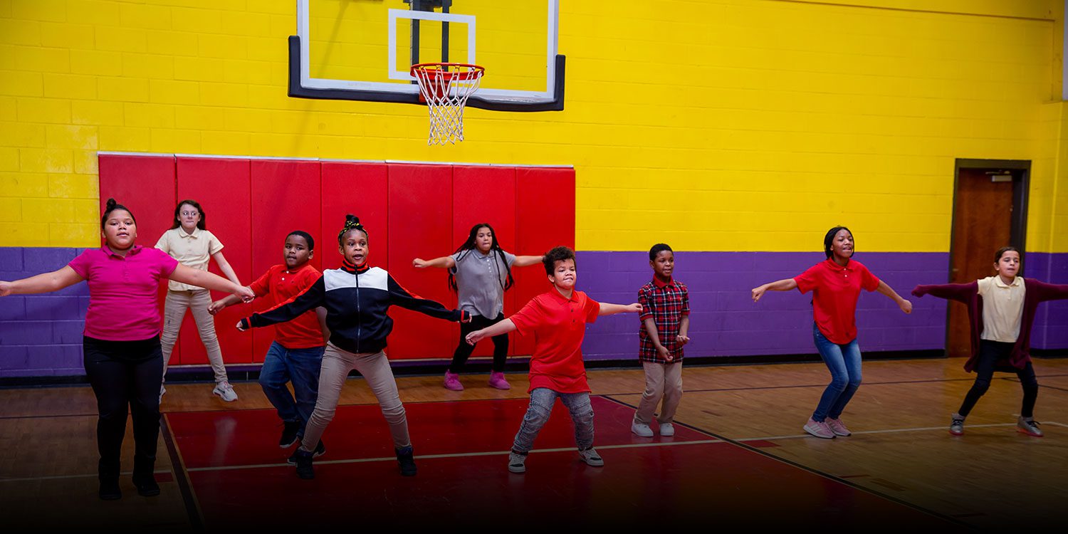 Group of smiling students dancing on the basketball court